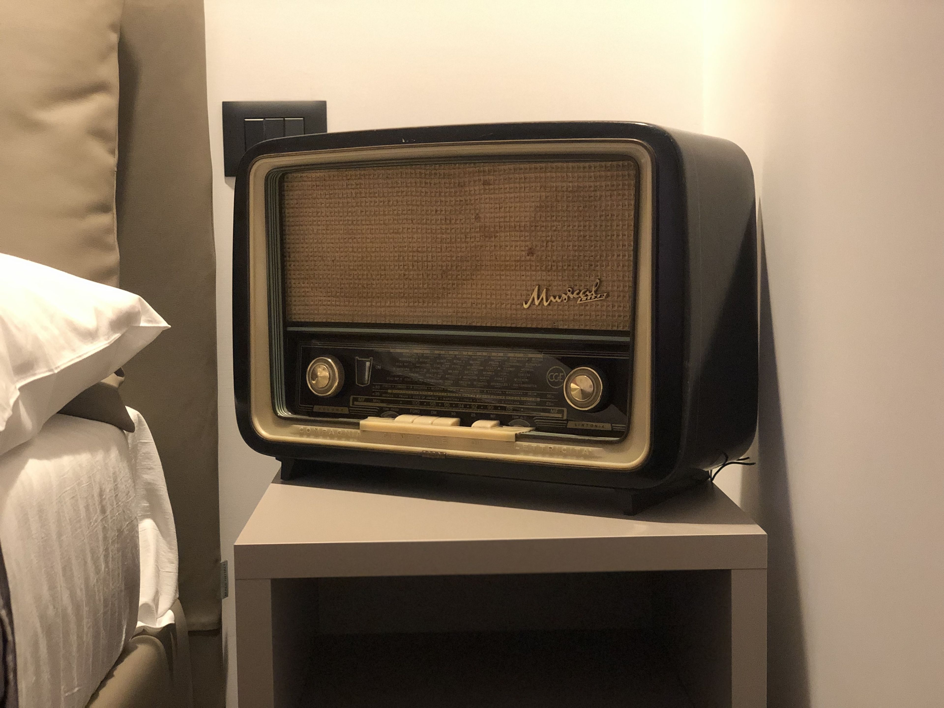 A vintage radio on a bedside table in a hotel room.