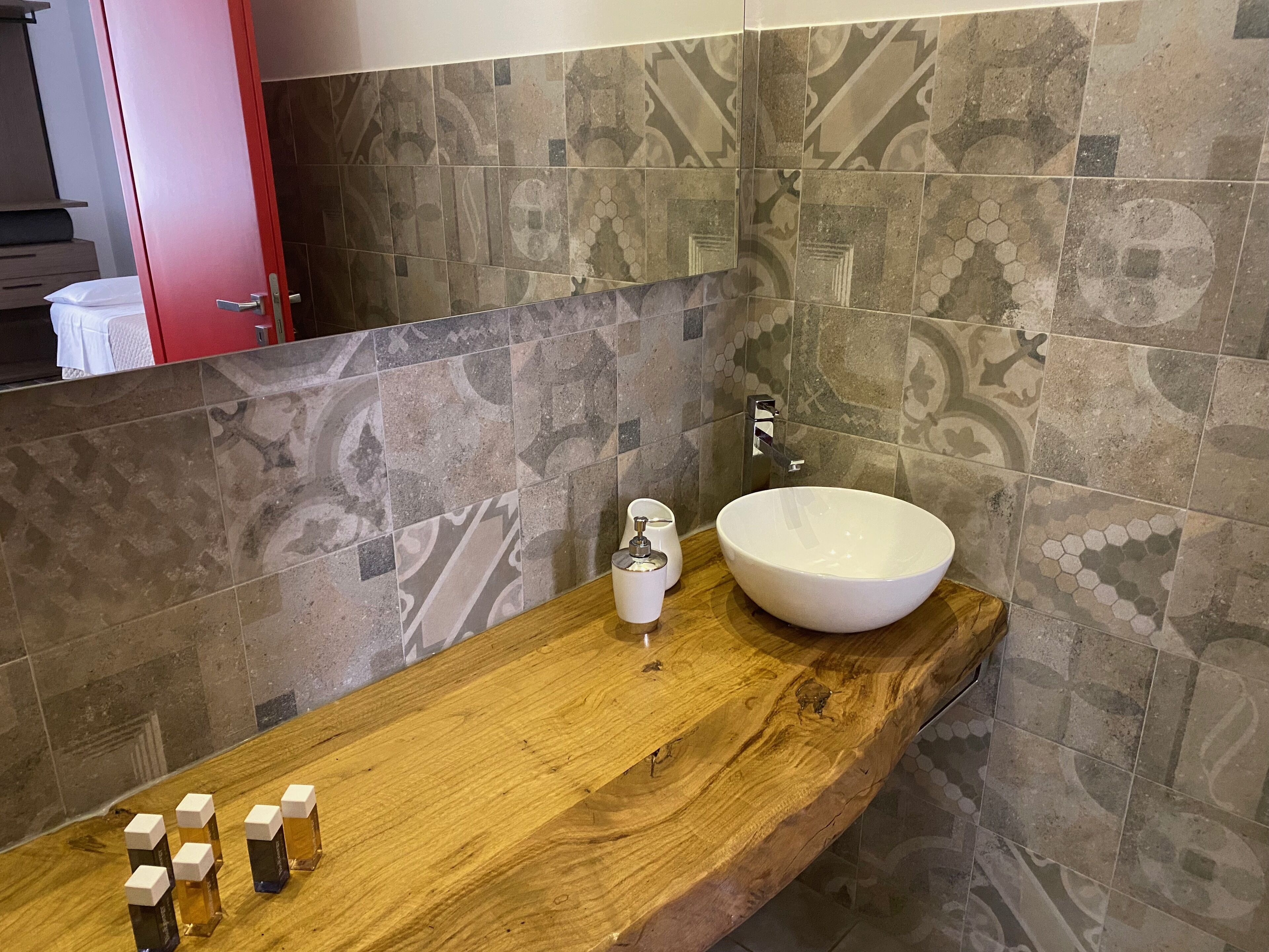A bathroom with a wooden vanity, a large white sink, and a mirror.