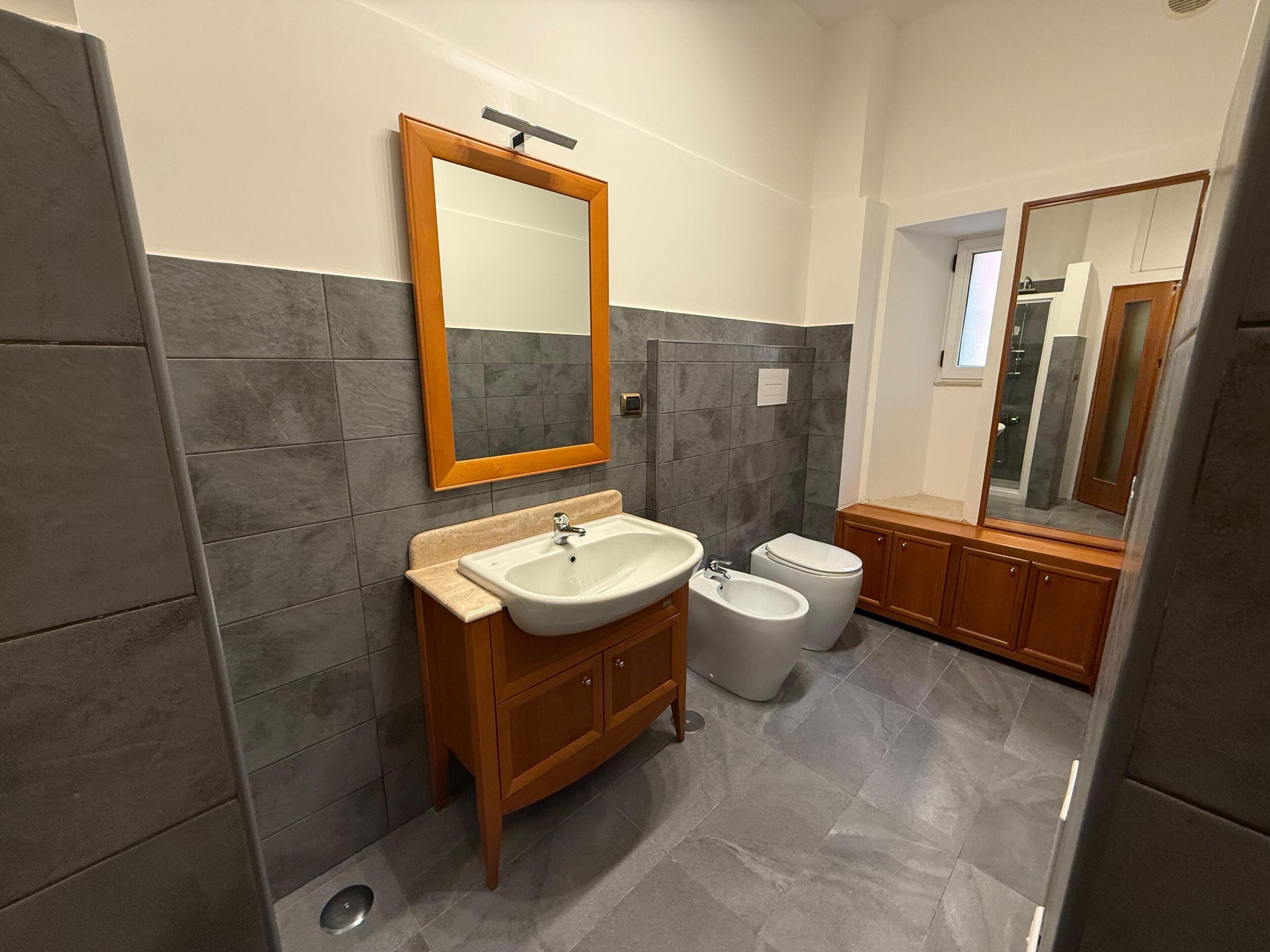 A modern bathroom with a vanity, sink, bidet, and a large mirror.
