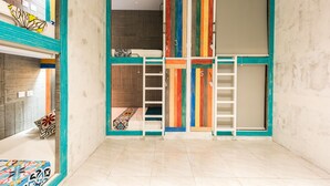 A room with a bunk bed, a ladder, and a colorful wardrobe with numbered doors. - Write Hostel (Penida Island)