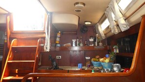 Een kleine keuken met houten kastjes, een spoelbak en een raam.
