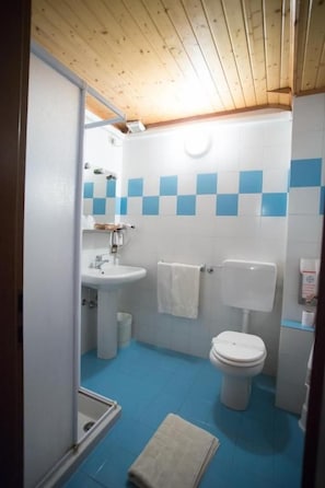 Un baño con lavamanos blanco, inodoro y suelo con azulejos azules.