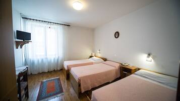 A room with two beds, a television, a small table, and a rug.