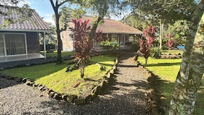 Un patio con un camino de grava, un árbol pequeño y un edificio con tejado de baldosas.
