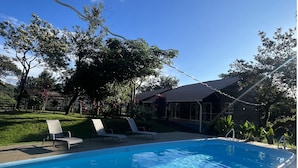 Una piscina con agua cristalina, rodeada por una terraza con sillas de descanso.