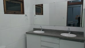 Une salle de bain avec deux lavabos, un miroir et une fenêtre.
