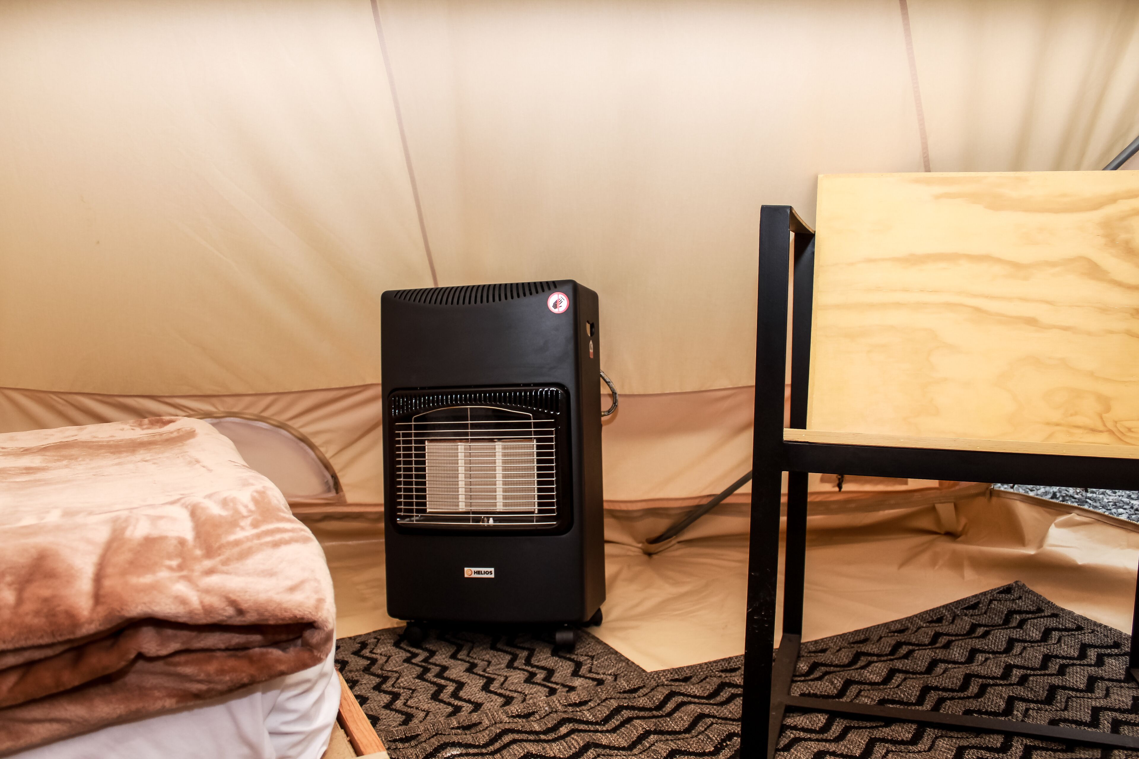 A compact room with a bed, a heater, and a table.