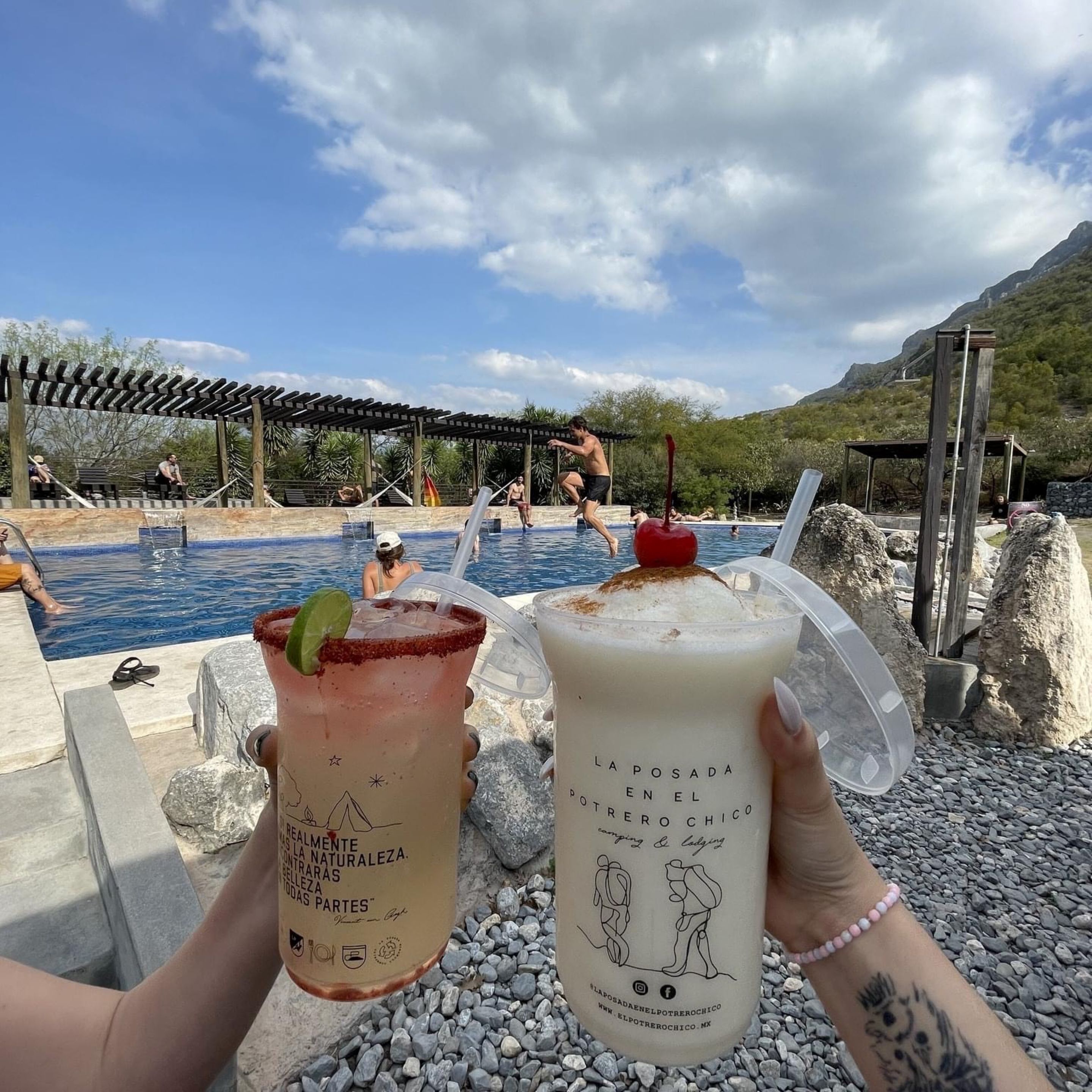 Deux boissons avec leurs étiquettes, une piscine et des personnes à l’arrière-plan.