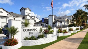 A Coronado Inn with a well-maintained lawn, a clear sign, and a flag. - Coronado Inn (Coronado)