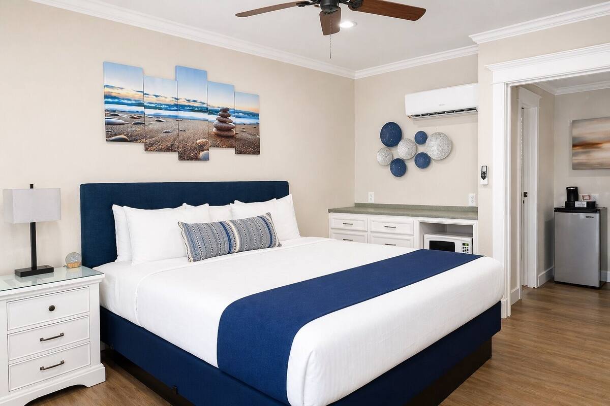 Une chambre à coucher comprenant un lit, une table de chevet, une commode et un mur décoré de différents objets.