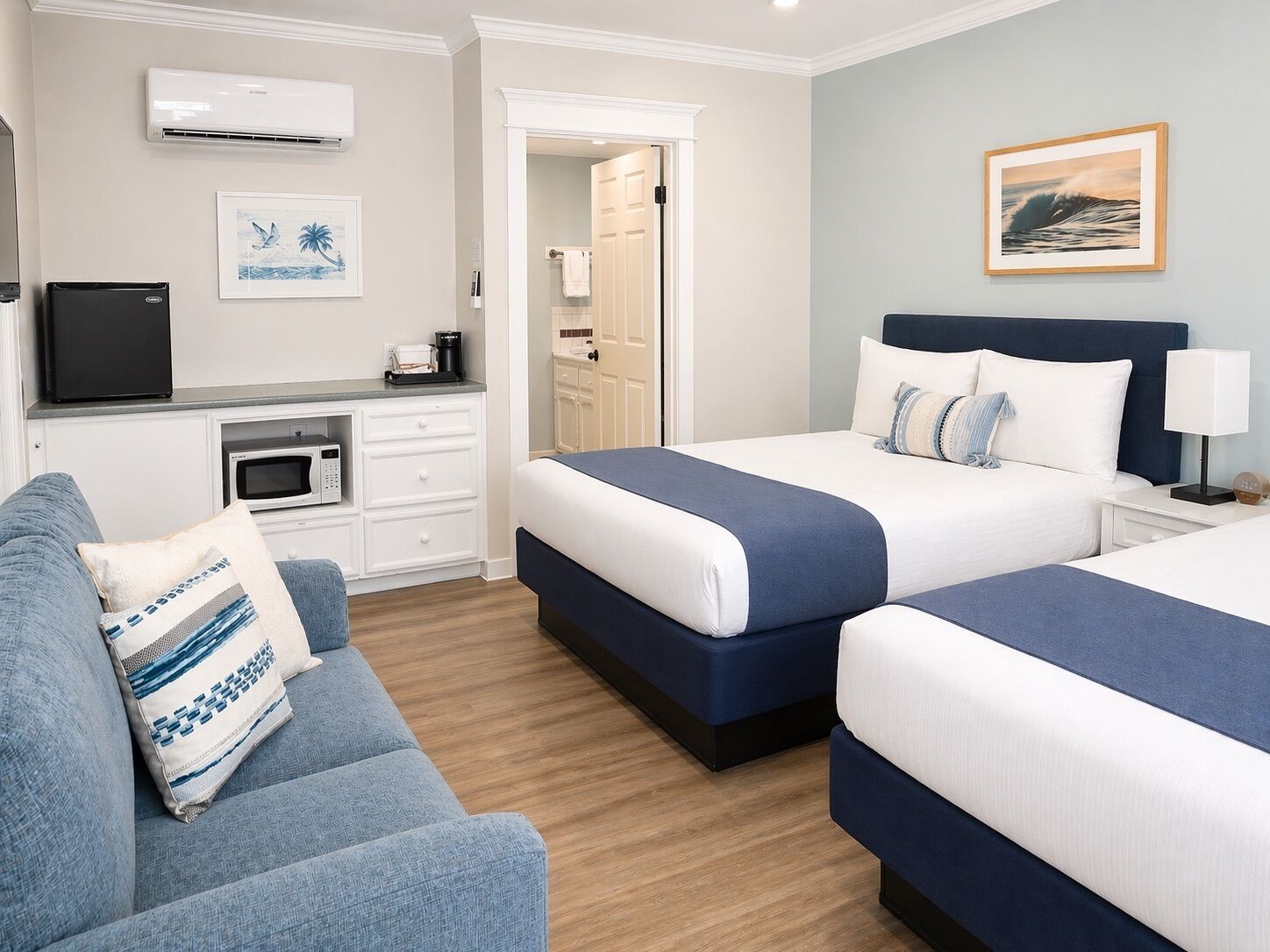 Une chambre d’hôtel avec deux lits, un canapé, une kitchenette et une salle de bain.