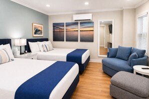 A hotel room with two beds, a sofa, a small table, and a TV. - Coronado Inn (Coronado)