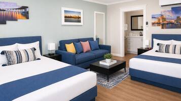 A hotel room with two beds, a sofa, a coffee table, and artwork on the walls.