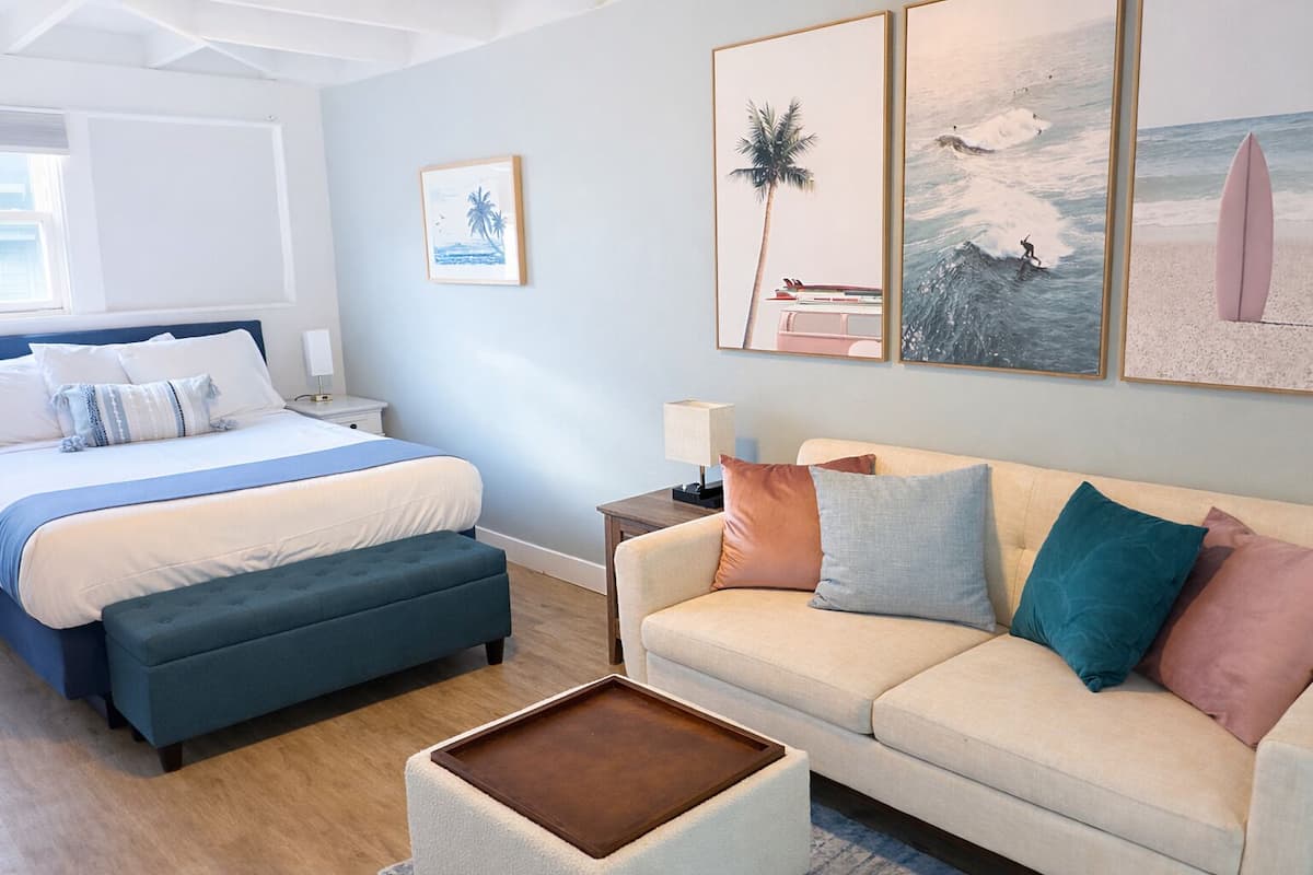 Une chambre à coucher comprenant un lit, une table de chevet, une commode, un canapé, une table basse et des œuvres d’art murales.