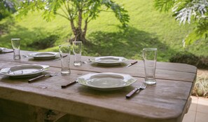 A wooden picnic table set outdoors with plates, glasses, and cutlery. - Premier Residence Hplus Long Stay (Brasília)
