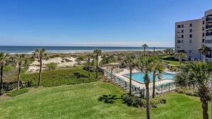 A resort with a pool, palm trees, and a view of the beach and ocean. - A116-amelia-surf-and-racquet (Fernandina Beach)