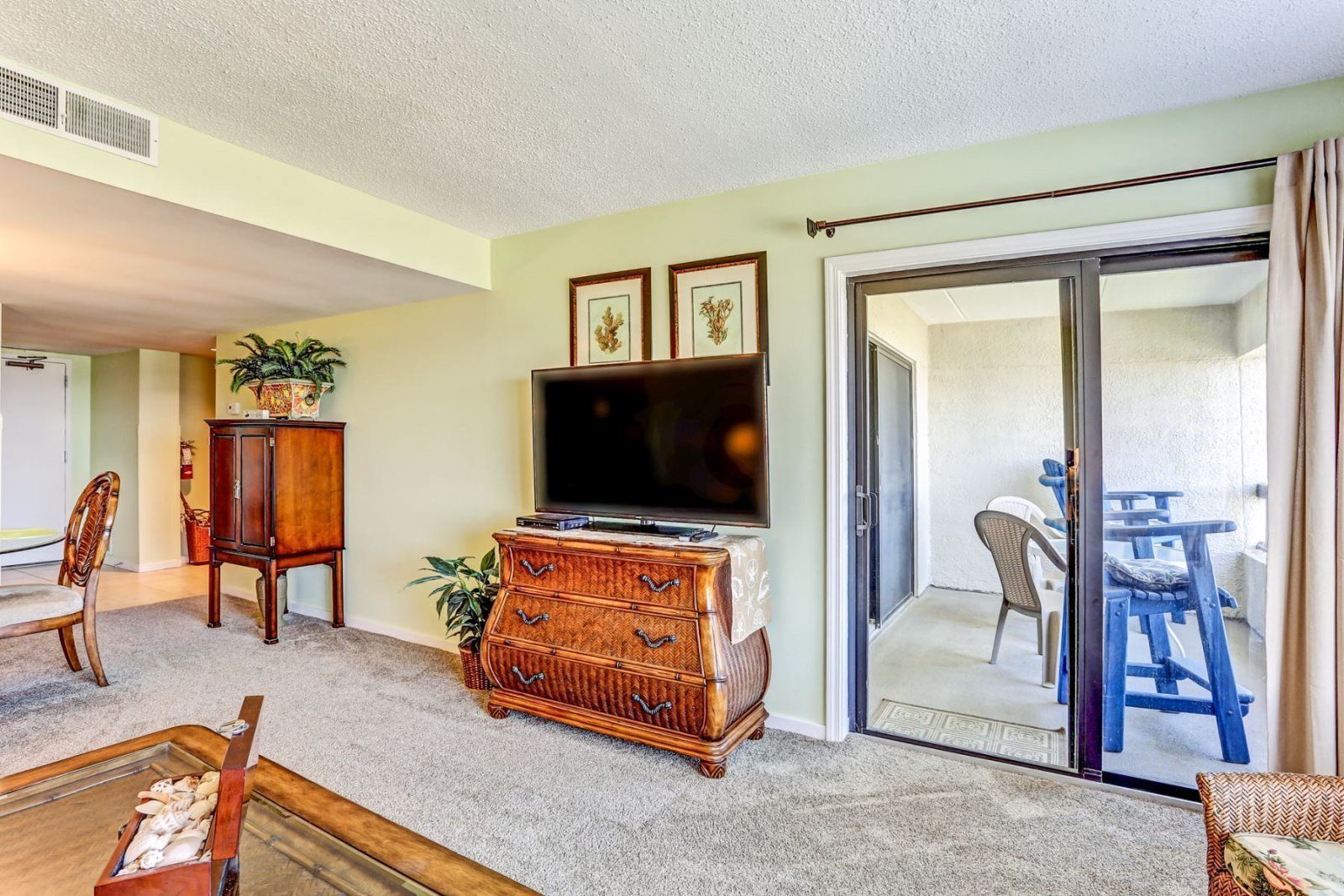 A living room with a television, wooden furniture, and a sliding glass door leading to an outdoor area.