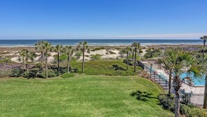 A beachfront property with a swimming pool, palm trees, and a view of the ocean. - A116-amelia-surf-and-racquet (Fernandina Beach)