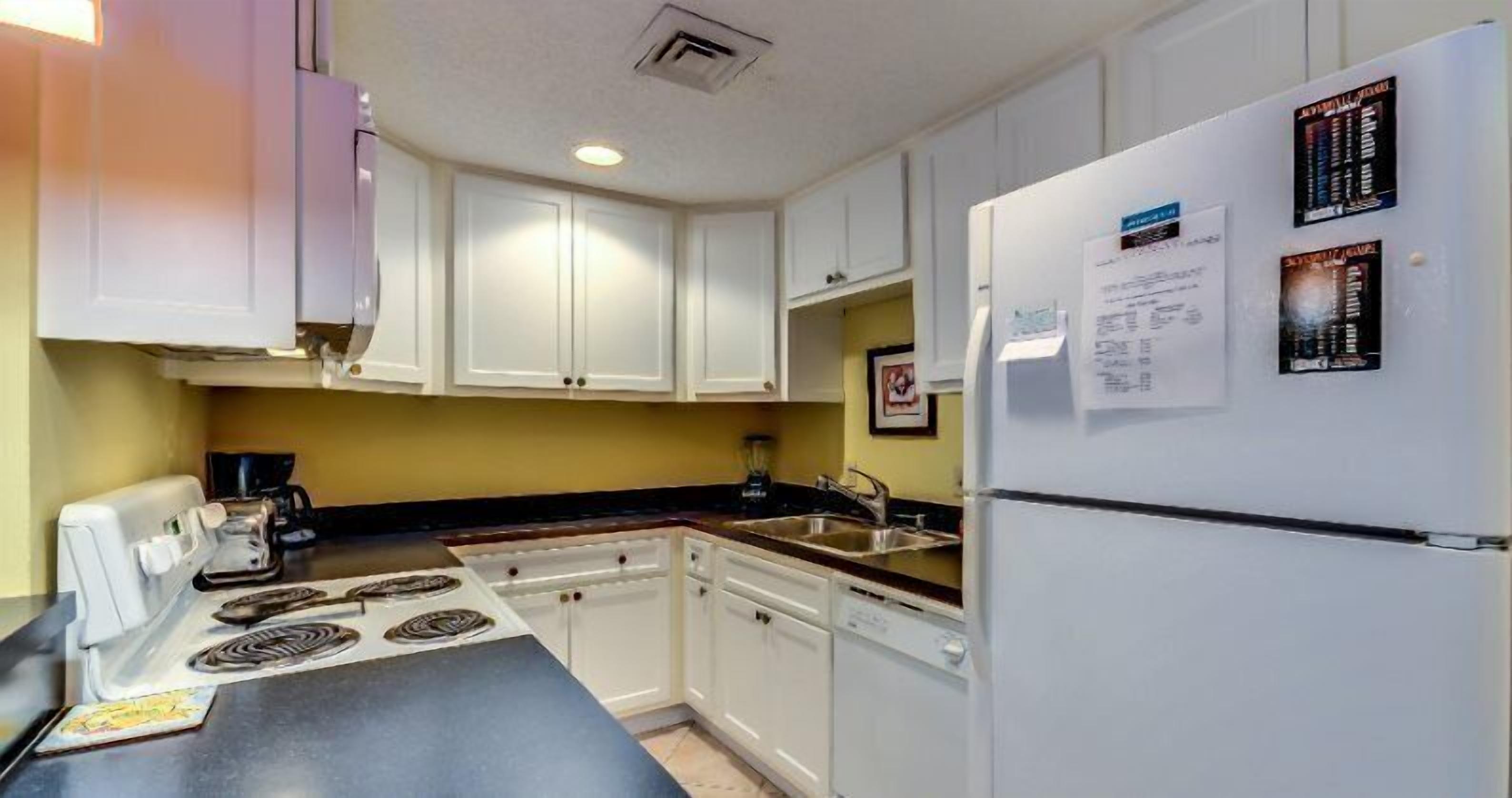 A kitchen with white cabinets, a refrigerator, a stove, and a coffee maker.