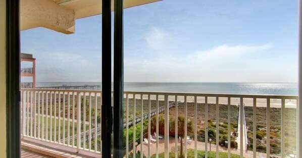 A balcony with a view of the beach and ocean.
