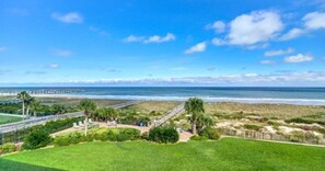 Une vue sur la côte, avec une plage, une promenade en bord de mer et une zone herbeuse parsemée de sentiers.