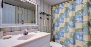 A bathroom with a sink, mirror, and shower curtain. - 303-atlantis-on-amelia (Fernandina Beach)