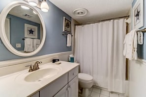 A bathroom with a white sink, a mirror, a toilet, and a shower curtain. - 2126 Beachwood (Fernandina Beach)