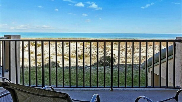 Un balcon avec vue sur une plage et l’océan.