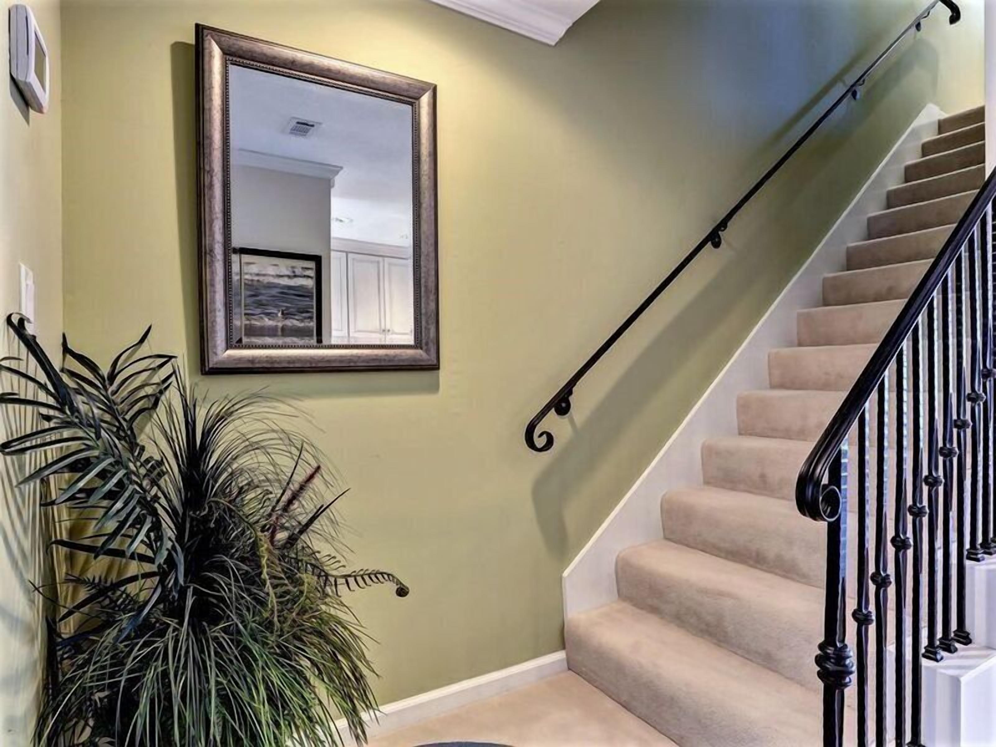 A staircase with beige carpeted steps and a black metal railing.