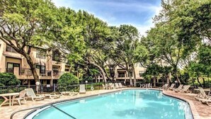 Une piscine entourée d’arbres et un bâtiment doté de balcons.