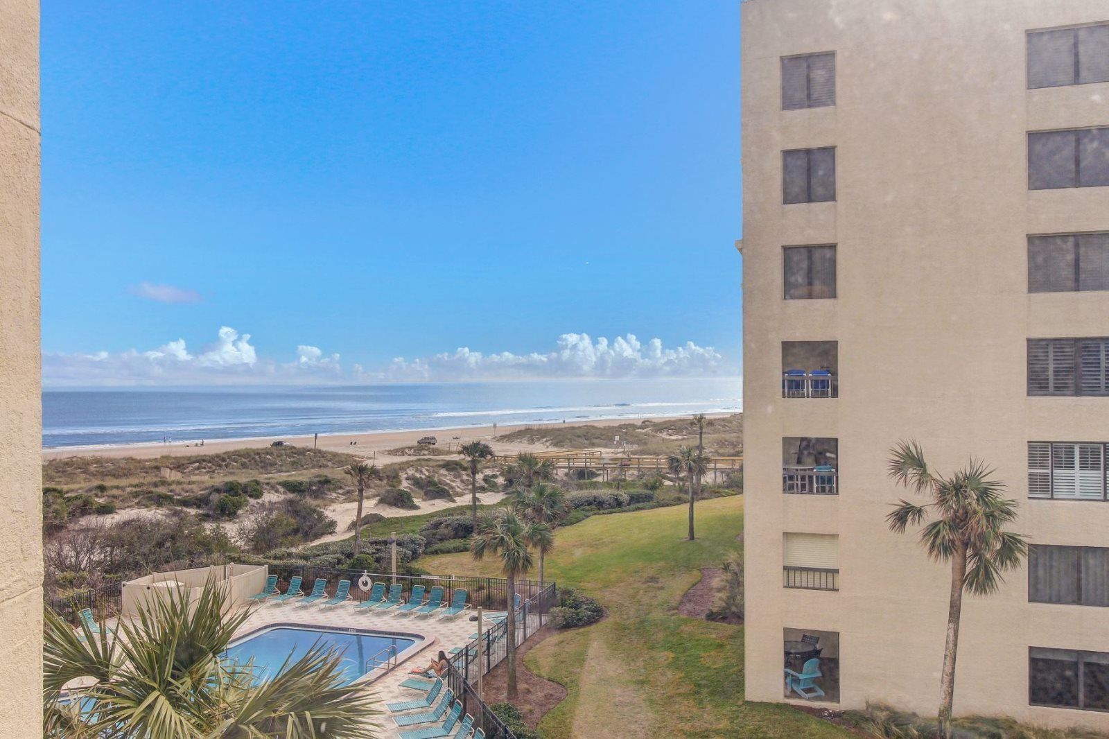 Um hotel com piscina, vista para a praia e um edifício com várias varandas.