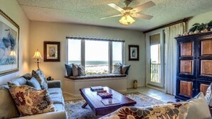 A living room with a view of the beach, a ceiling fan, and a large cabinet. - 1637-38-sea-dunes (Fernandina Beach)