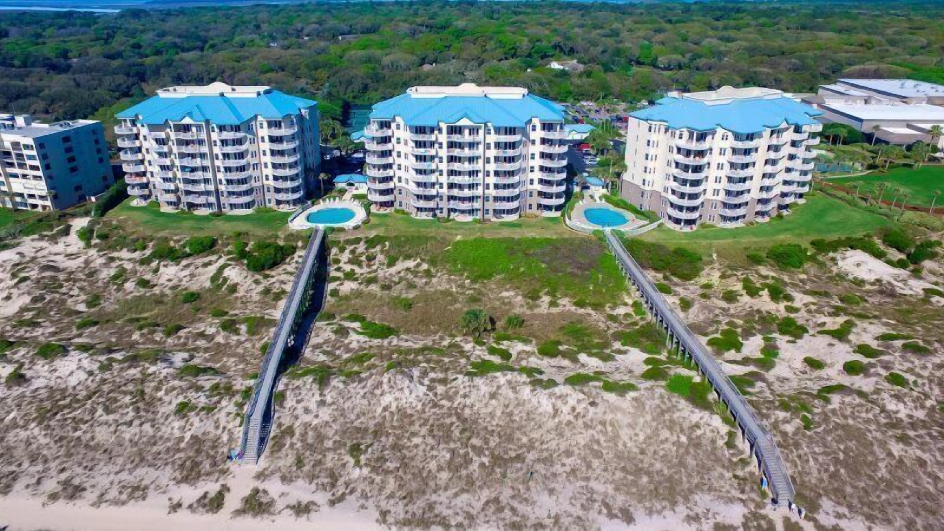 A coastal hotel complex with multiple high-rise buildings, each featuring balconies and a pool area.