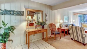 A living room with a wooden desk, wicker chair, striped armchair, and a sofa. - 2135-beachwood (Fernandina Beach)