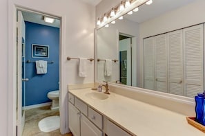 A bathroom with a white sink, a large mirror, and a blue wall.