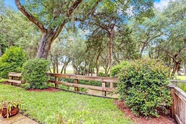 A park with a wooden fence, various trees, and well-maintained grass.