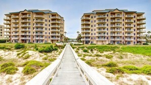 A beachfront hotel with a central walkway leading to the buildings. - 69-ocean Place (Fernandina Beach)