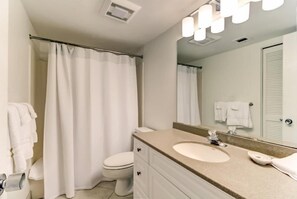 Een badkamer met toilet, wastafel, spiegel en douchegordijn.