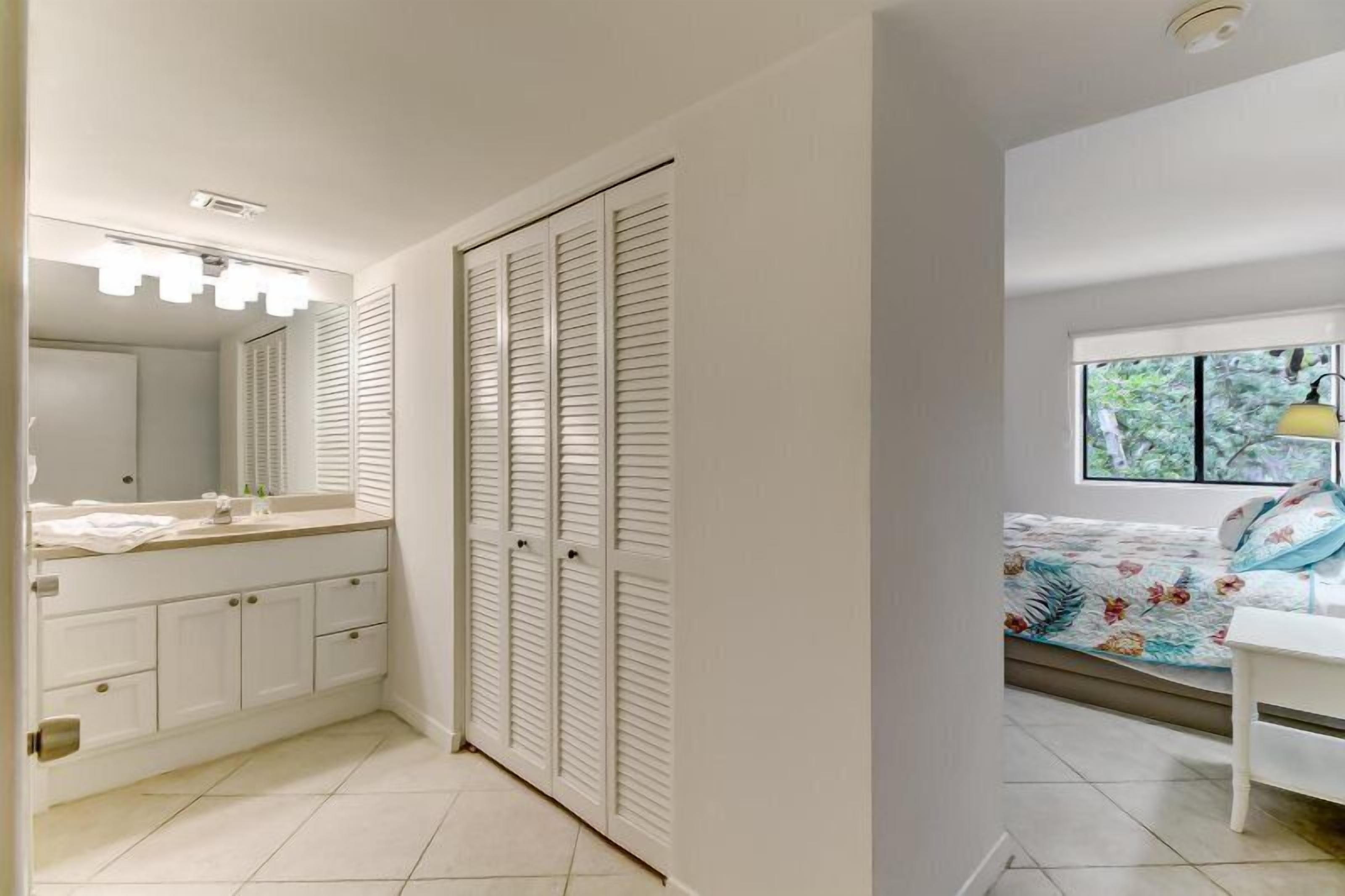 A bedroom with a bed, a window with a view of greenery, a bedside table, and a nightstand.