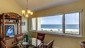 A dining area with a view of the ocean, a chandelier, and a wooden headboard with a painting.