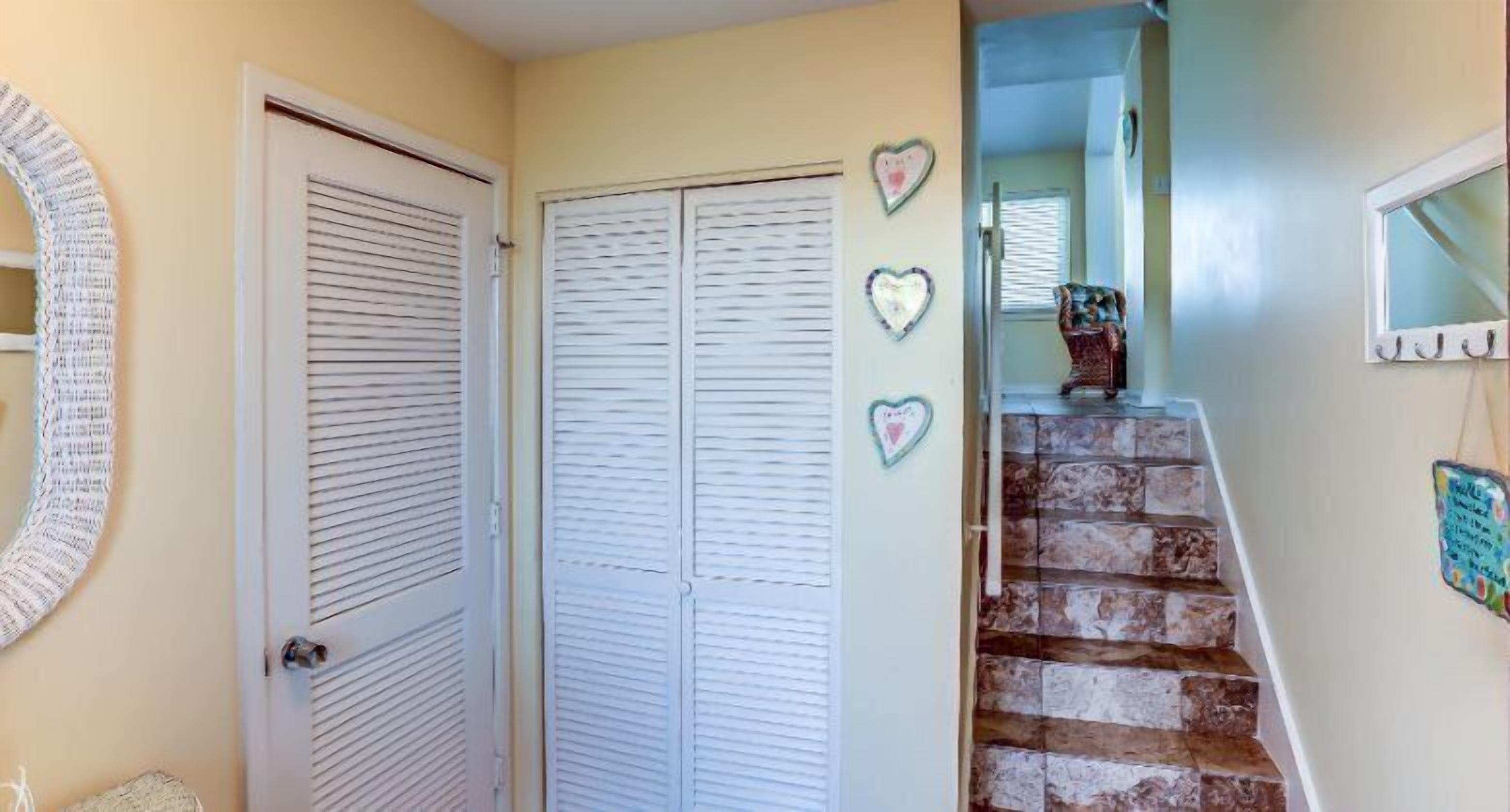 A staircase with a stone finish, a white door with horizontal blinds, and heart-shaped decorations on the wall.