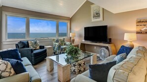 A living room with a large window, a flat-screen TV, and a fan. - 1114-beach-walker (Fernandina Beach)