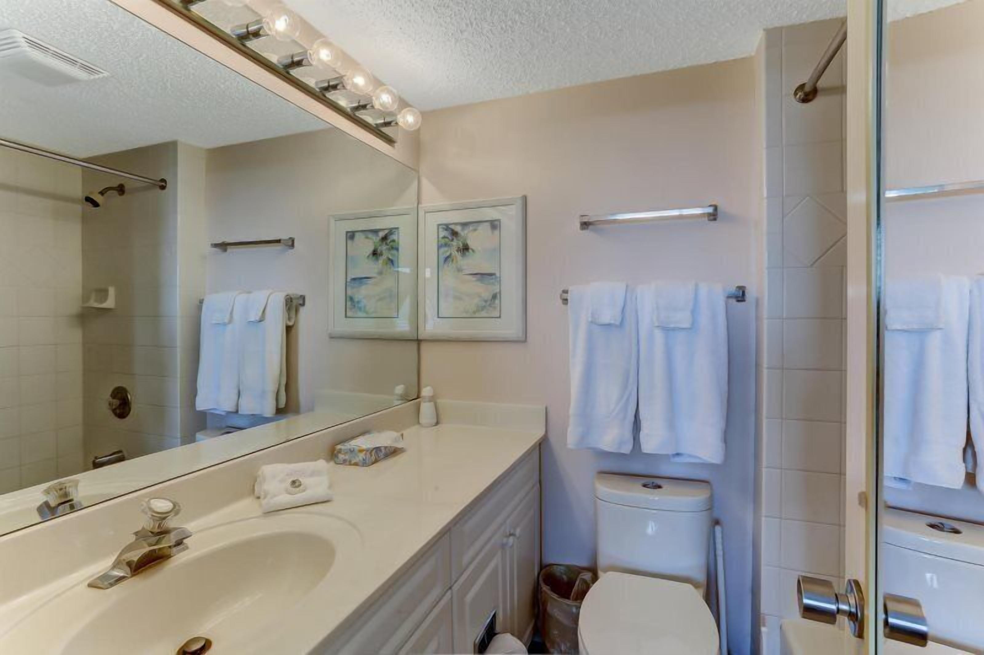 A bathroom with a large mirror, a bathtub, a toilet, and a shower.