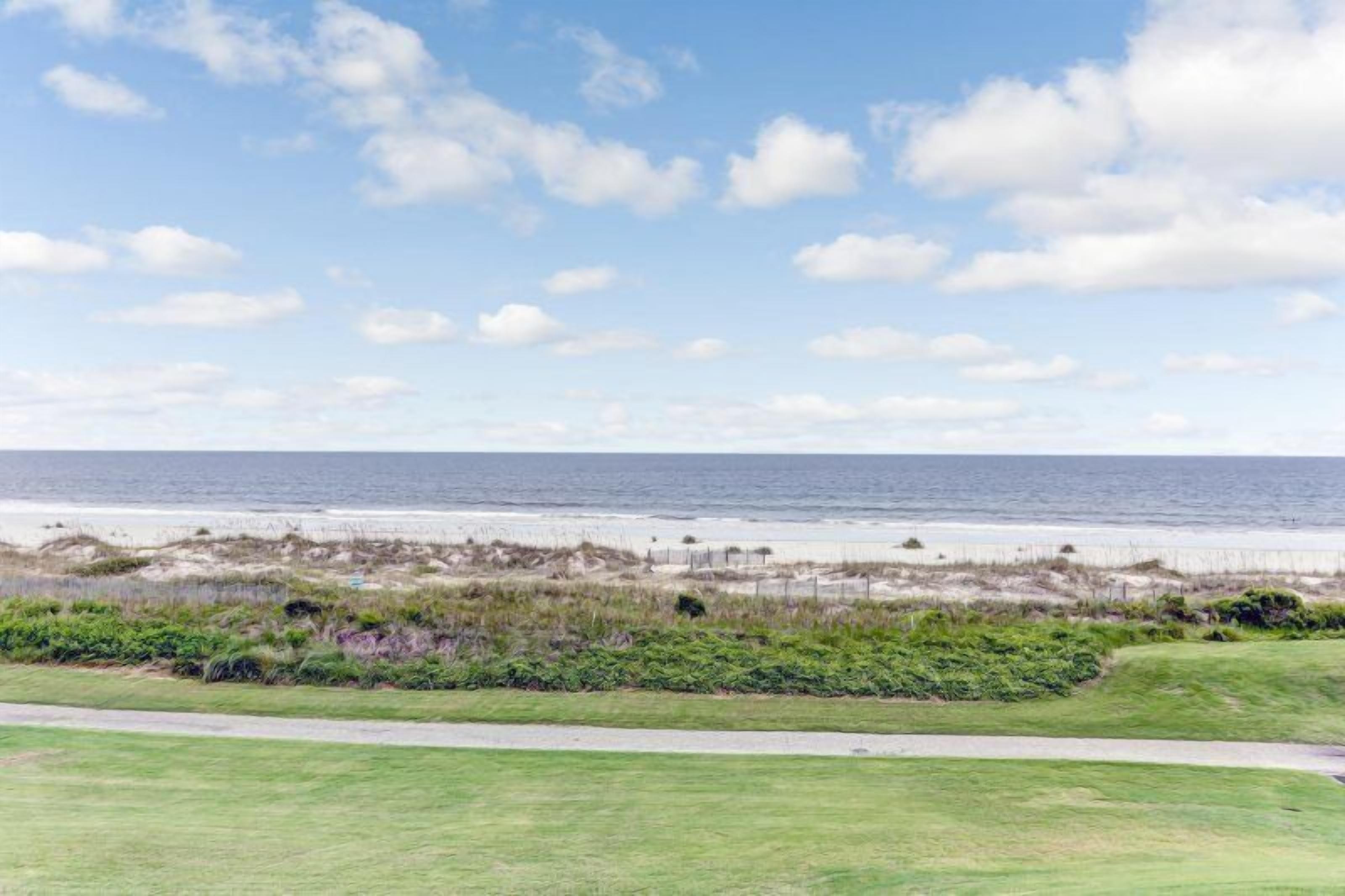 A coastal view with a grassy area, a path, and the ocean in the background.