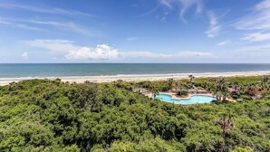 A resort with a pool surrounded by dense greenery, overlooking a beach and the ocean. - 1114-beach-walker (Fernandina Beach)