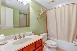 A bathroom with a white sink, a toilet, and a shower curtain. - 1839-turtle-dunes (Fernandina Beach)