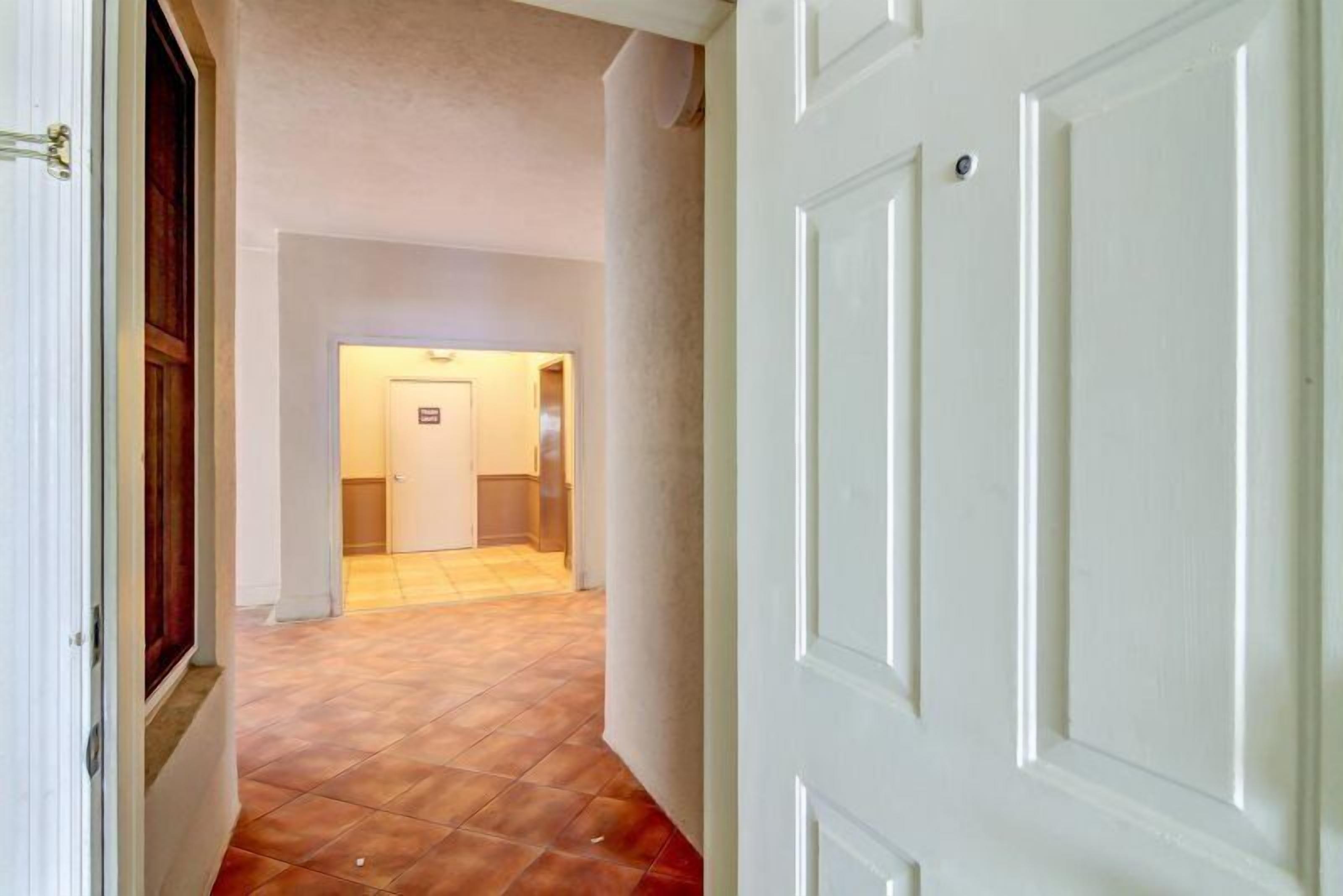 A hallway with a tiled floor leading to a room with a door.