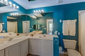 A bathroom with a large mirror, vanity with two sinks, and a toilet. - 13-ocean-place (Fernandina Beach)