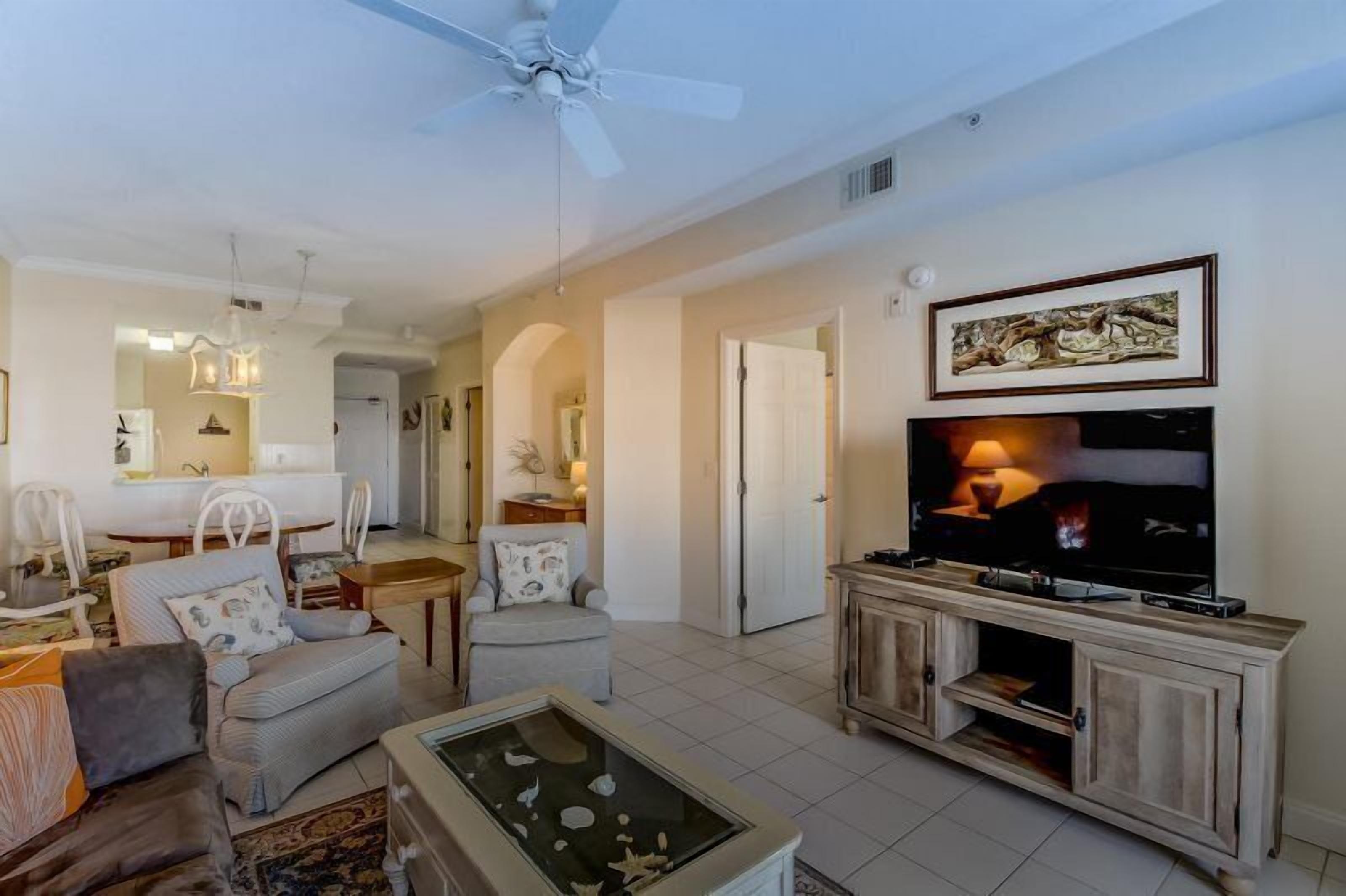 A living room with a TV, seating area, and a dining space.