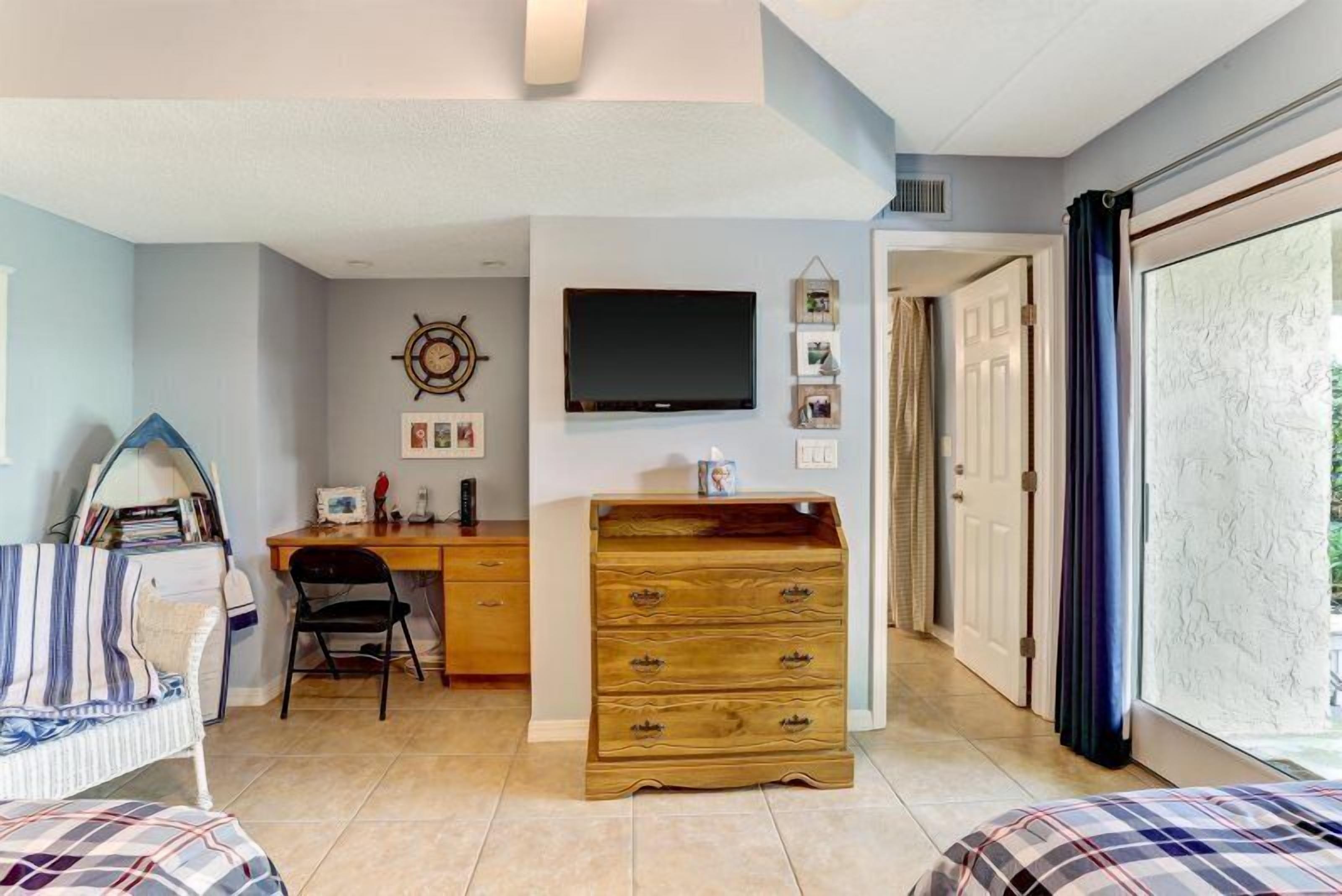 A room with a bed, a desk, a chair, a television, and a wardrobe.